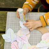 Child using the OkoNorm solvent free all purpose craft glue placing it one the back of paper leaf rubbings.