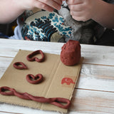 Child making heart shapes using the brown Okonorm play dough. 
