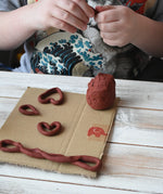Child making heart shapes using the brown Okonorm play dough. 