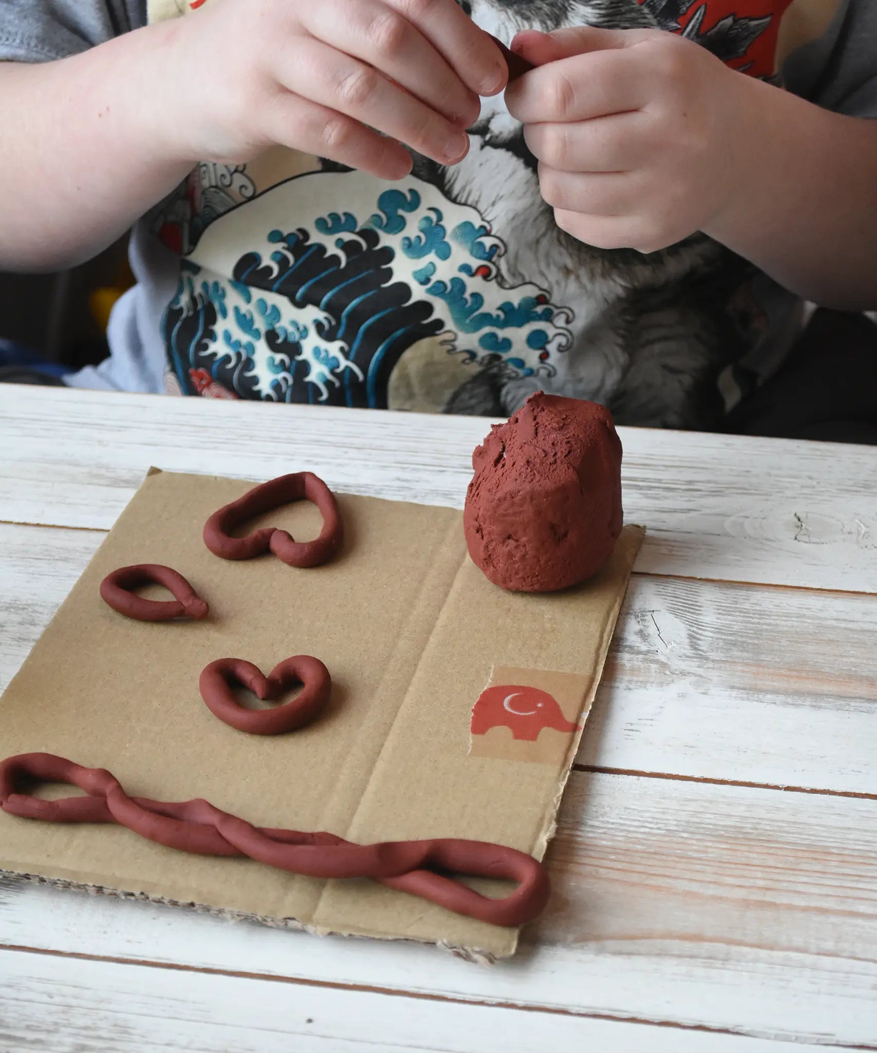 Child making heart shapes using the brown Okonorm play dough. 