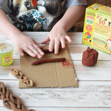 Child rolling brown Okonorm play dough into long sausage shapes. 
