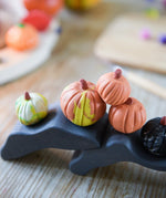 Pumpkins made from OkoNorm modelling clay placed on wooden toys.