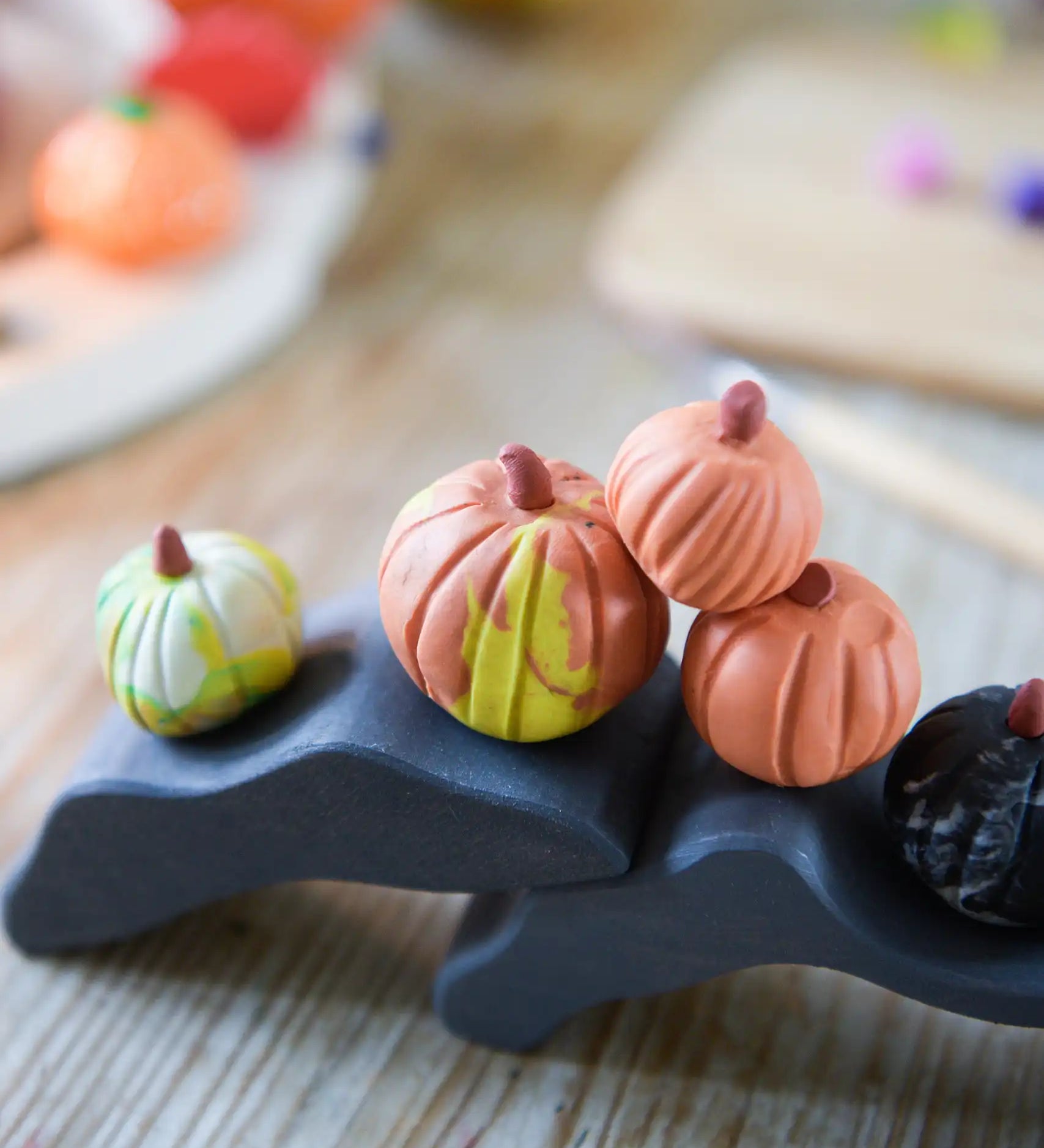 Pumpkins made from OkoNorm modelling clay placed on wooden toys.