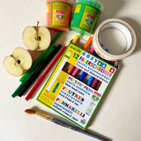 Pack of OkoNorm 12 felt tip pens placed besides Okonorm paints, Babipur tapes and a cut apple.