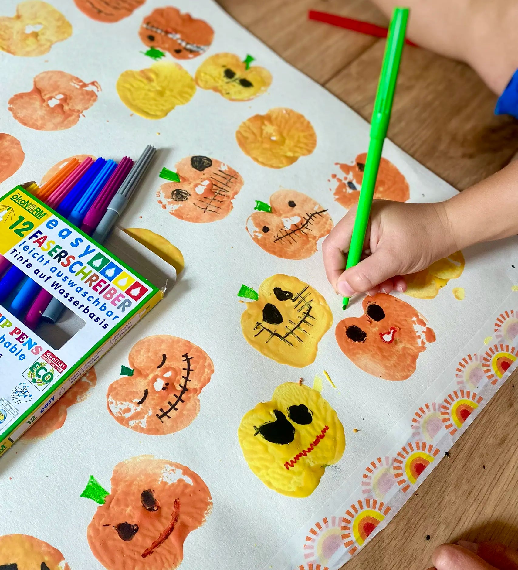 Child using the green pen from the OkoNorm 12 felt tip pens  to paint details on pumpkin prints.