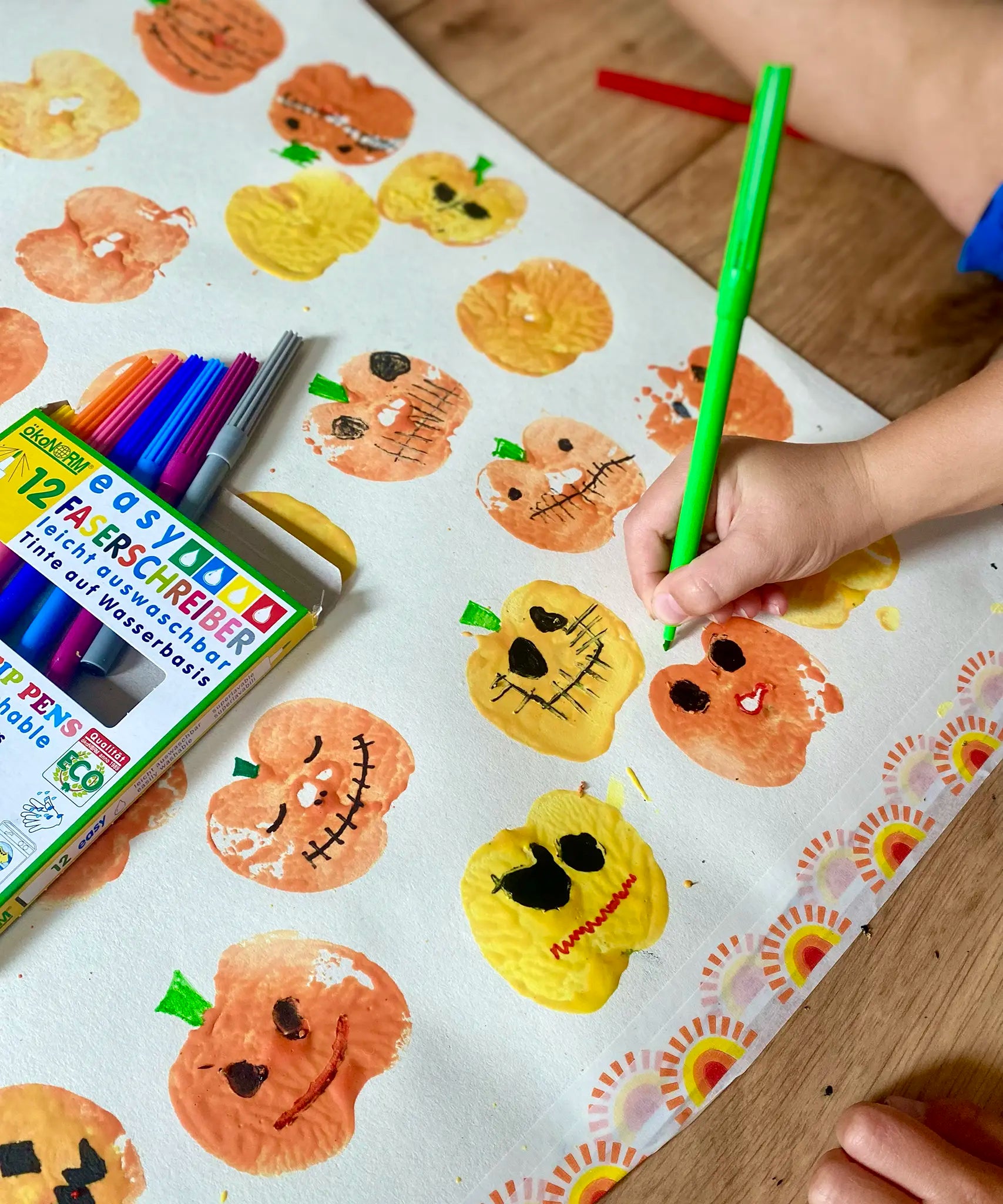 Child using the green pen from the OkoNorm 12 felt tip pens  to paint details on pumpkin prints.