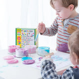 Children painting with the OkoNorm pastel colours non-toxic finger paints. One pot each of blue, purple, light pink and fuschia.