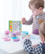 Children painting with the OkoNorm pastel colours non-toxic finger paints. One pot each of blue, purple, light pink and fuschia.