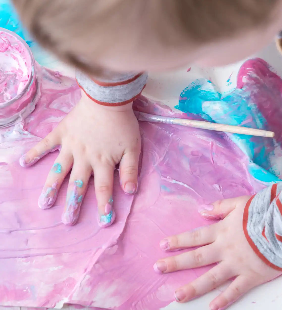 Child with his hand in pink coloured  OkoNorm non-toxic Finger Paints. 