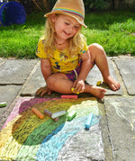 Child drawing a rainbow on slabs with the Okonorm chalks. 