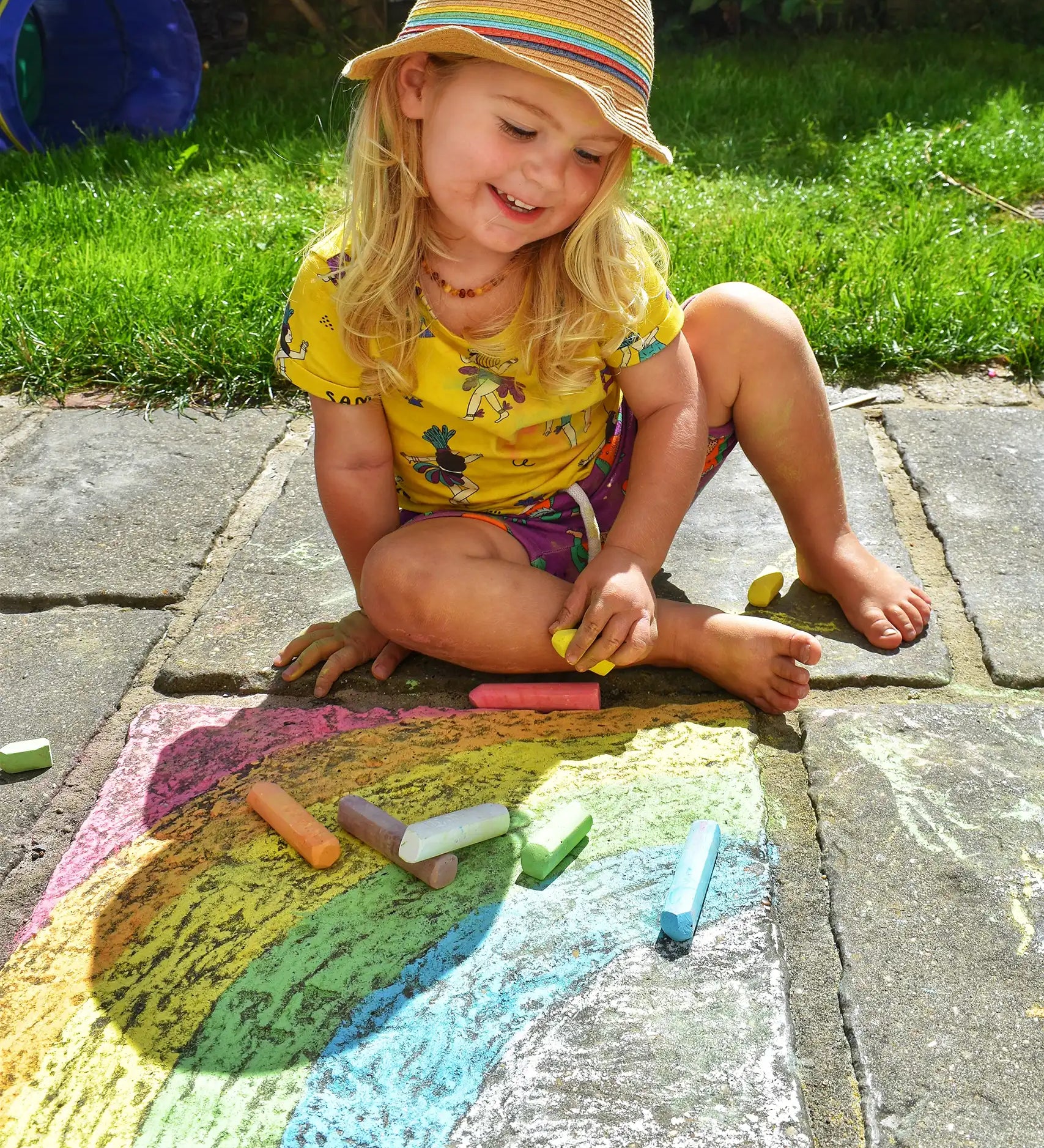 Child drawing a rainbow on slabs with the Okonorm chalks. 