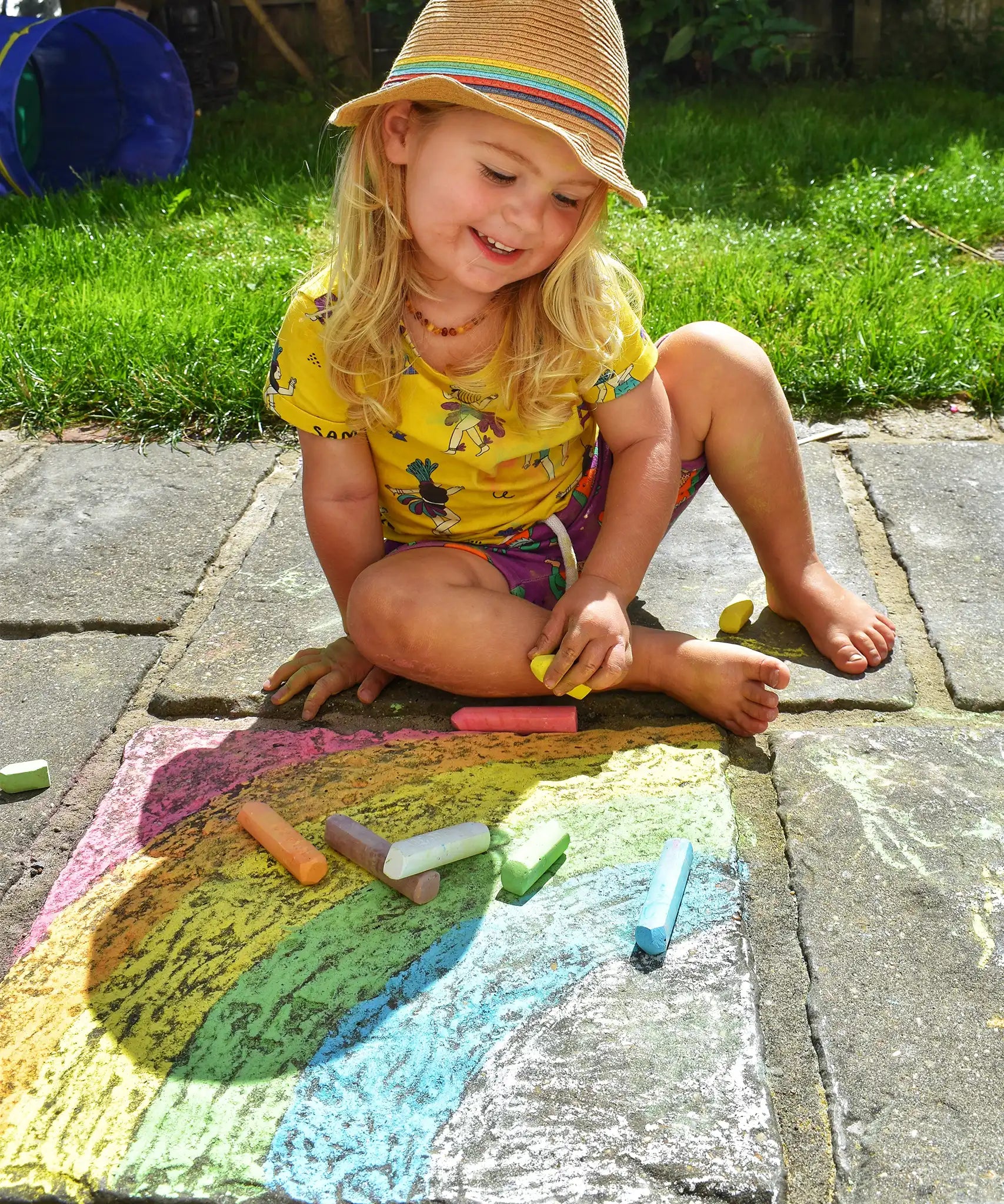 Child drawing a rainbow on slabs with the Okonorm chalks. 