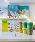 OkoNorm finger paints in 6 unicorn  colours stacked on a table with the packaging box behind them with an Ostheimer unicorn wooden toy figure placed on top.  