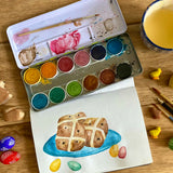 Watercolour hot cross buns painting created using the Okonorm 12 colour watercolour paints in a travel tin.