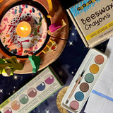 OkoNorm watercolour paints set in 6 colours placed on a table next to a decorated Grimm's celebration ring and Medenka beeswax crayons.