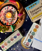 OkoNorm watercolour paints set in 6 colours placed on a table next to a decorated Grimm's celebration ring and Medenka beeswax crayons.