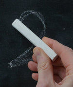 Person drawing a number 2 on a black surface with white Okonorm chalkboard chalk.