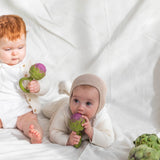 One baby sitting holding an Oli & Carol Artichoke Rattle Teether toy with another baby lying by their side chewing on an Oli & Carol Artichoke Rattle Teether