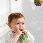 A baby cluting onto and chewing the Oli & Carol Cauliflower Rattle Teether