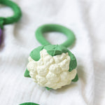 An Oli & Carol Cauliflower Rattle Teether placed an a white muslin