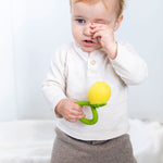 A child holding onto a Oli & Carol Lemon Rattle Teether