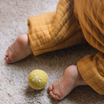 An Oli & Carol lemon baby sensory ball on carpet, a babies can be seen crawling away.