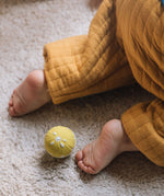 An Oli & Carol lemon baby sensory ball on carpet, a babies can be seen crawling away.