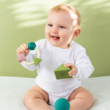 Baby playing with Oli & Carol X Bauhaus Movement Floating Geometric Blocks in Pastel colours with a teething ring in other hand