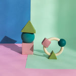 Oli & Carol X Bauhaus Movement Floating Geometric Blocks in Pastel colours and teething ring pictured on a pastel pin