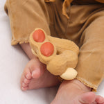 Close up of the oli and carol childrens rubber peanut food toy on a toddlers legs on a white background