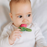 Close up of a baby chewing on the oli and carol ramonita radish teether on a white bed