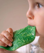 A baby chewing on the Oli & Carol green coloured Chlorophyll Leaf Baby Teether