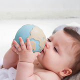 A baby holding the Oli &amp; Carol Earthy The World Ball in their hands.