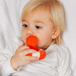 A child chewing on the Oli & Carol Flo The Floatie Duck Red.