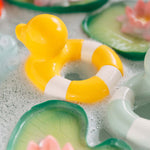 Oli & Carol Flo The Floatie Duck Yellow in water with bubbles.
