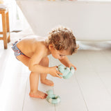 Child playing with the Oli & Carol Flo The Floatie Mint colour duck bath toys in a bathroom
