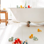 Oli & Carol Flo The Floatie Duck bath toys in various colours pictured in a bathroom
