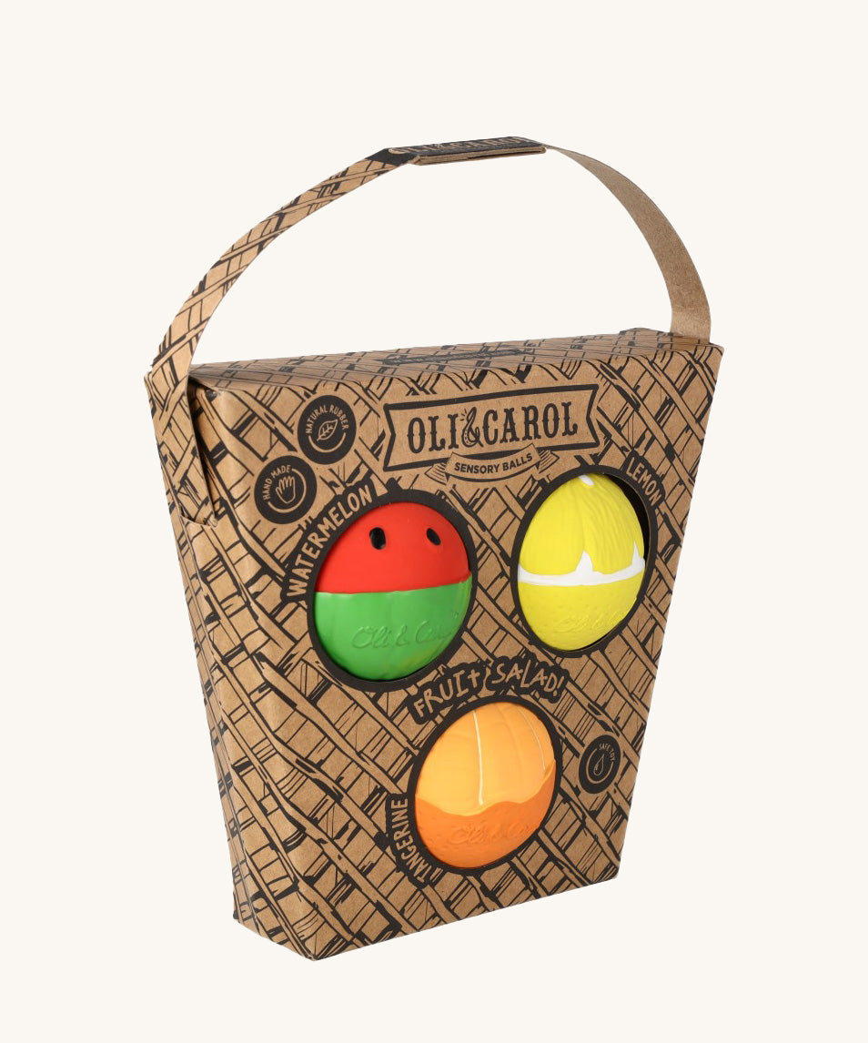 Oli & Carol Fruit Salad Baby Sensory Balls including a watermelon, lemon and tangerine in their cardboard basket shaped packaging