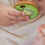 Baby clutching and chewing the Oli & Carol Jose Antonio The Kiwi Mini Baby Teether