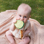 Baby clutching onto and chewing the Oli & Carol Pepino The Cucumber natural rubber toy