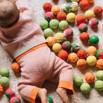 A baby laying on their front surrounded by Oli& Carol baby sensory balls