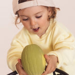 Toddler putting the Melon Oli & Carol 100% Natural Rubber Baby Sensory Ball  through a basketball hoop