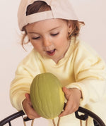 Toddler putting the Melon Oli & Carol 100% Natural Rubber Baby Sensory Ball  through a basketball hoop
