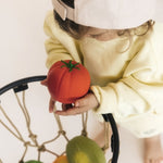 Child putting the Tomato Oli & Carol 100% Natural Rubber Baby Sensory Ball into a basketball hoop