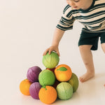 Child stacking a variety of Oli & Carol 100% Natural Rubber Baby Sensory Balls