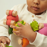 A child wheeling the Oli & Carol 100% Natural Rubber Emma the Eggplant Car in their hand