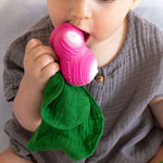 Close up of a young child holding the Oli & Carol Ramona radish doudou baby toy up to it's mouth