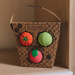 Oli & Carol Veggie Salad Baby Sensory Balls in their basket shaped cardboard packaging, a tomato, cabbage and a radish, placed on shelving