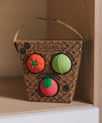 Oli & Carol Veggie Salad Baby Sensory Balls in their basket shaped cardboard packaging, a tomato, cabbage and a radish, placed on shelving
