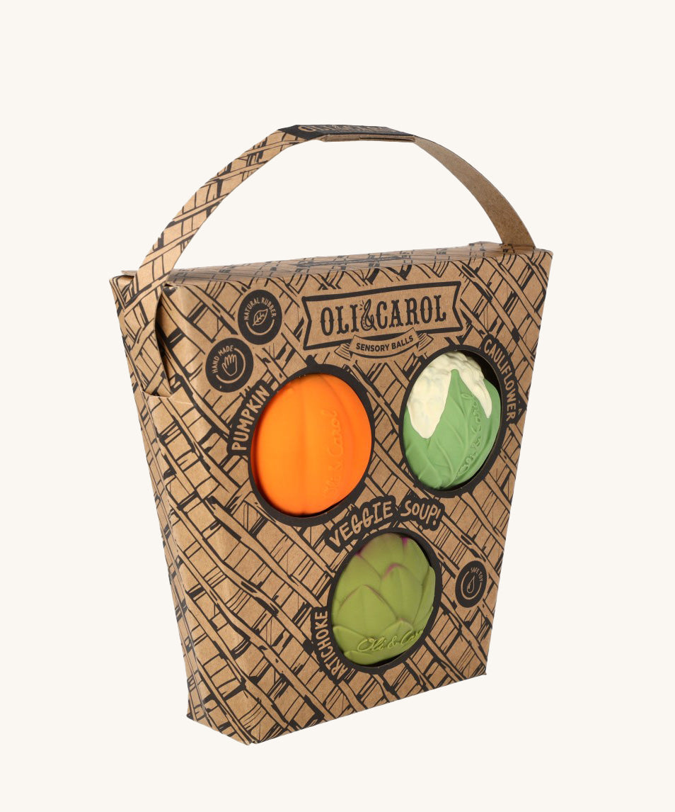 Oli & Carol Vegetable soup Baby Sensory Balls in their basket shaped cardboard packaging, a pumpkin, cauliflower and an artichoke. 